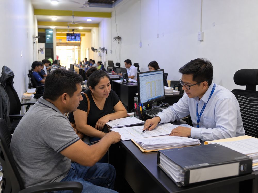 Asesor revisando una planilla con un empleador y un trabajador